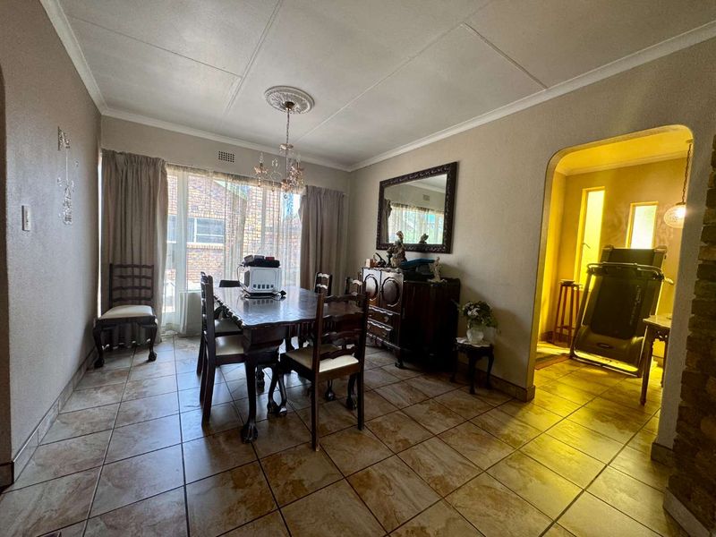 A dining room featuring tiled flooring, a decorative ceiling rose, and an arched entryway leading to an adjacent space.