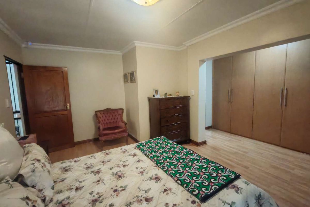 A bedroom featuring built-in wooden cupboards, laminate flooring, and crown molding, providing a functional and traditional living space.