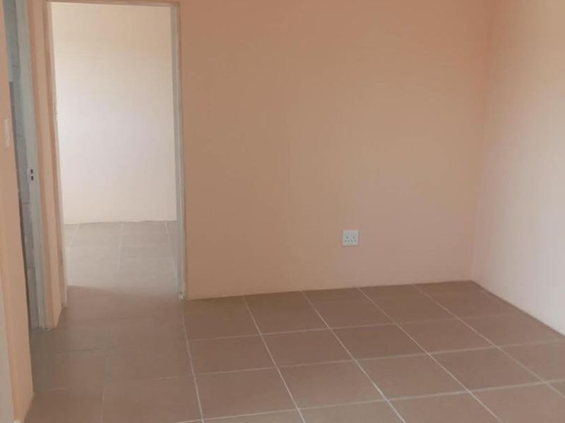 An empty bedroom featuring neutral wall paint and tiled flooring, providing a blank canvas for personalization.