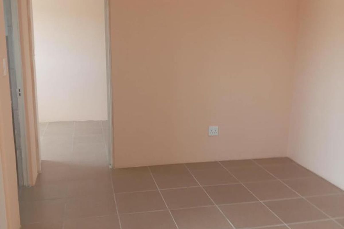 An empty bedroom featuring neutral wall paint and tiled flooring, providing a blank canvas for personalization.