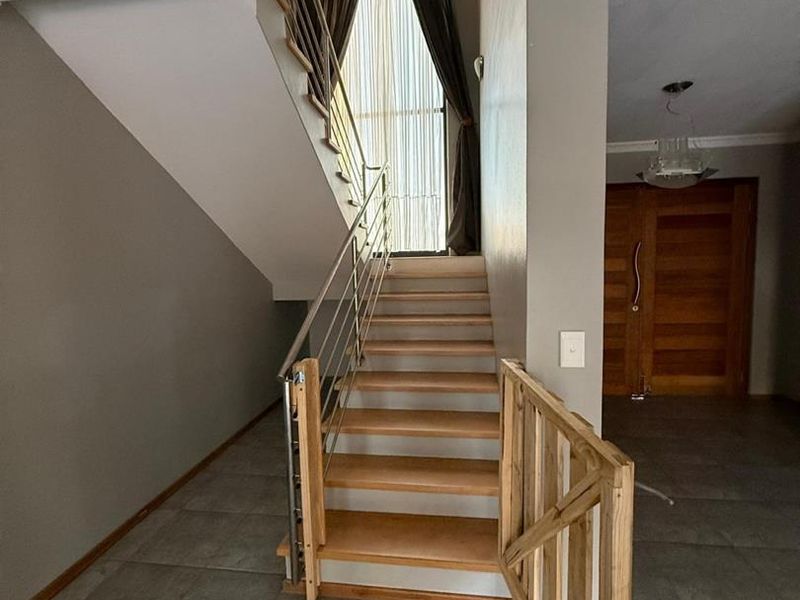 Entrance foyer featuring a tiled floor, a staircase with a stainless steel balustrade, and a solid wooden double front door.