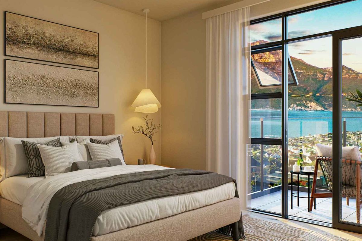 A modern bedroom featuring a large sliding glass door that opens onto a balcony with stunning coastal and mountain views.