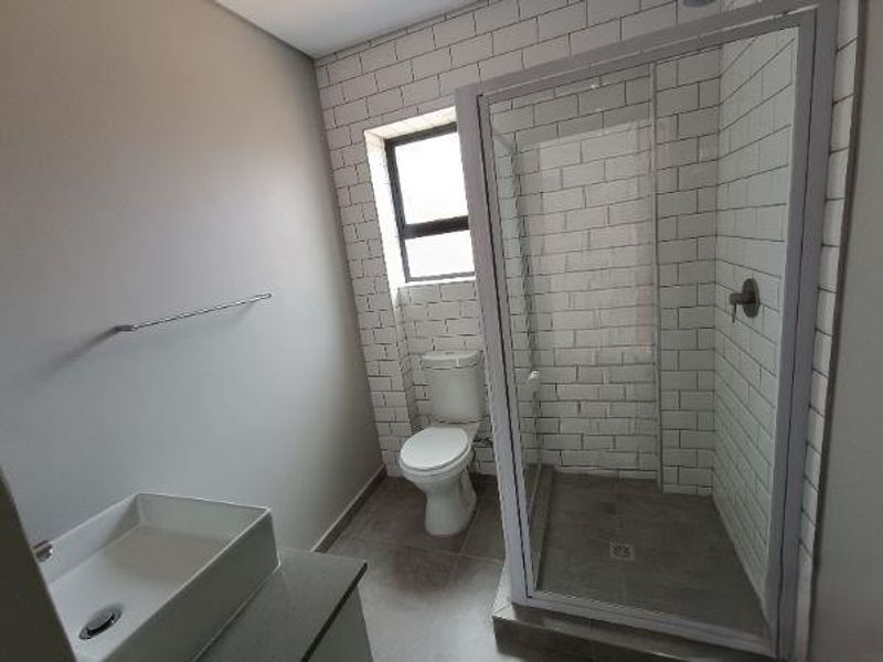 Modern bathroom featuring a glass-enclosed shower, subway tile wall finishes, a vessel sink on a vanity, and a standard toilet.