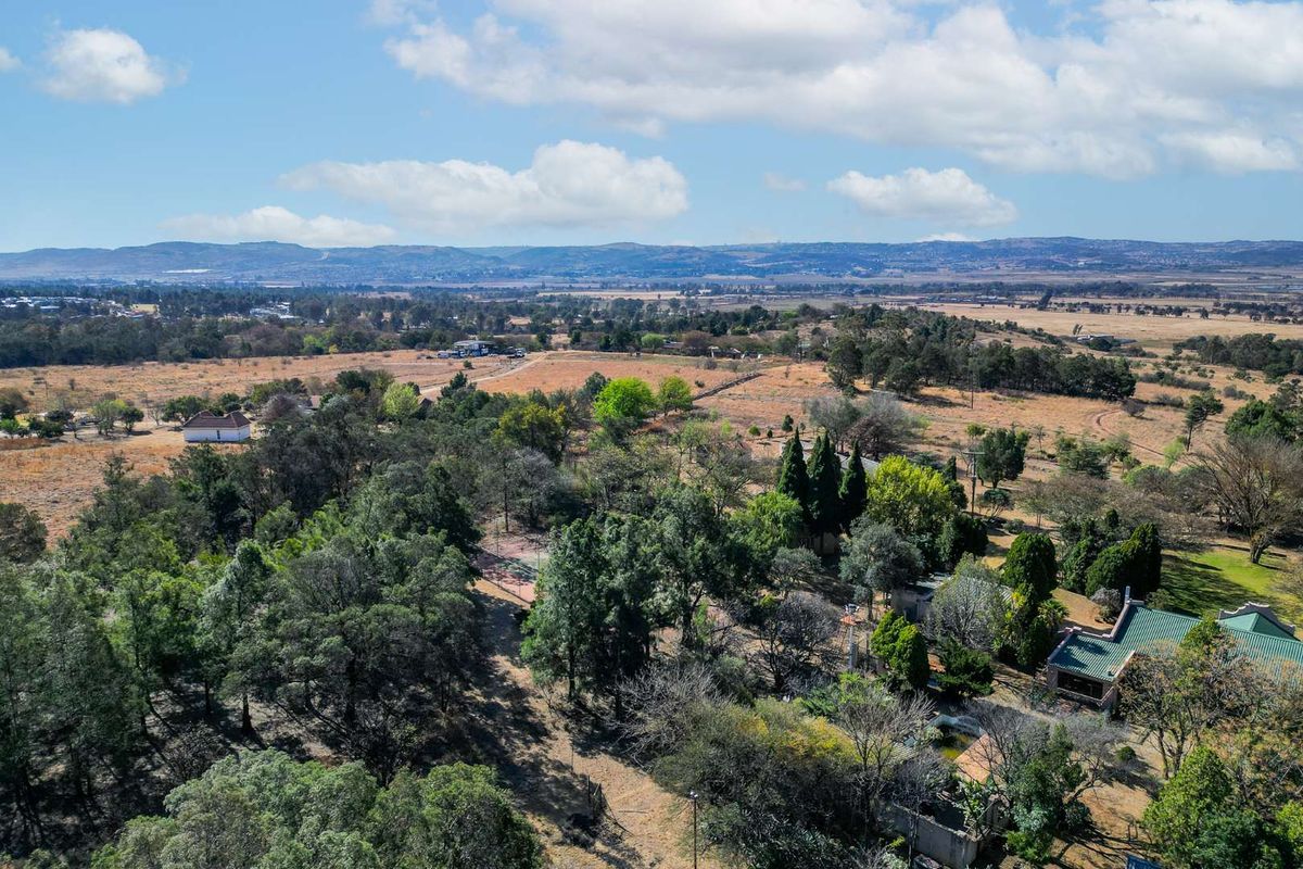An aerial view of the expansive residential property, showcasing mature trees, established landscaping, and surrounding rural landscape.