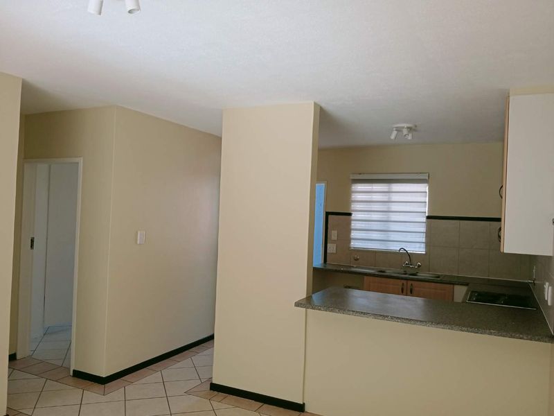 Open plan kitchen area featuring tiled flooring, neutral walls, and functional cabinetry with a breakfast bar counter.