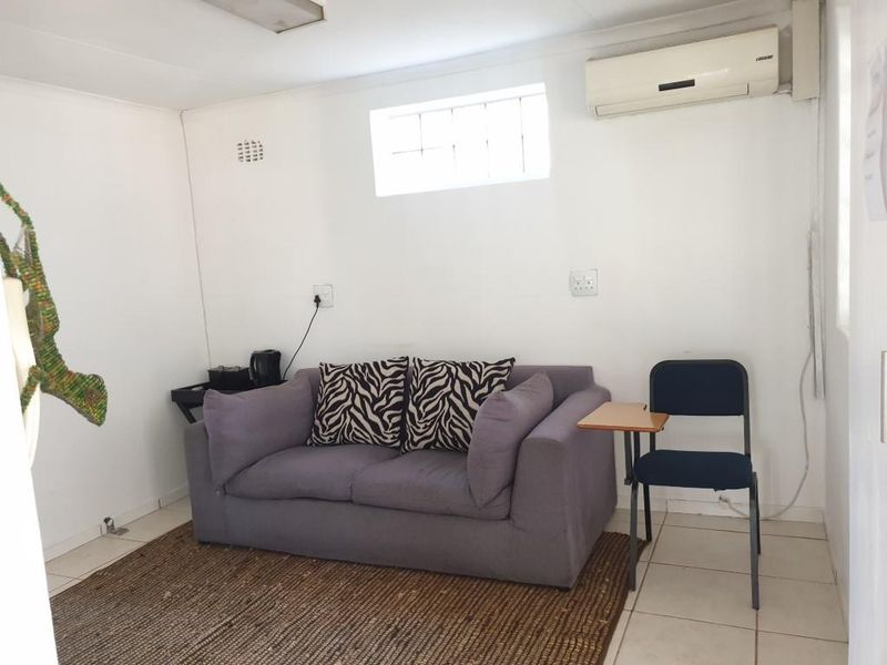 A functional office space featuring tiled flooring, a high-level window for natural light, and a wall-mounted split-system air conditioning unit.