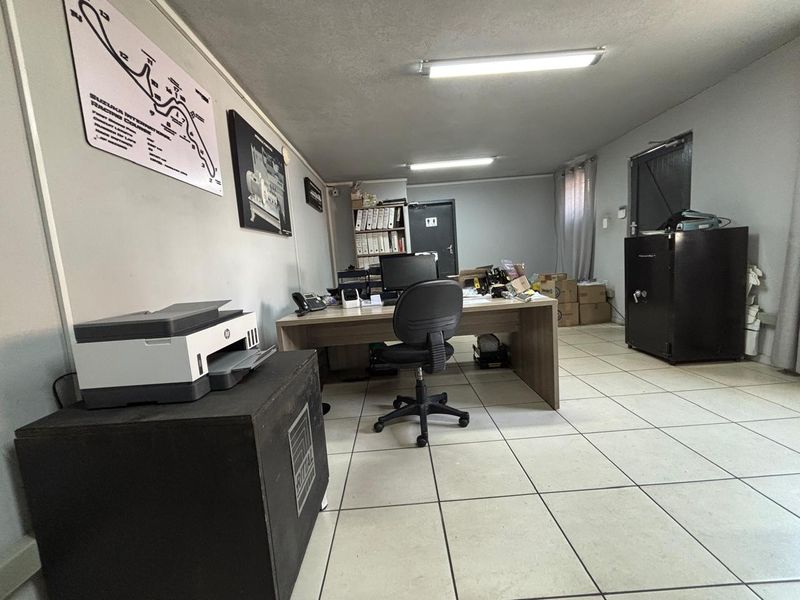 Functional industrial office space featuring ceramic floor tiles, fluorescent lighting, and built-in storage shelving.