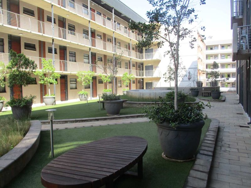 A well-maintained communal courtyard area within an apartment complex, featuring artificial turf, paved pathways, and established landscaping.