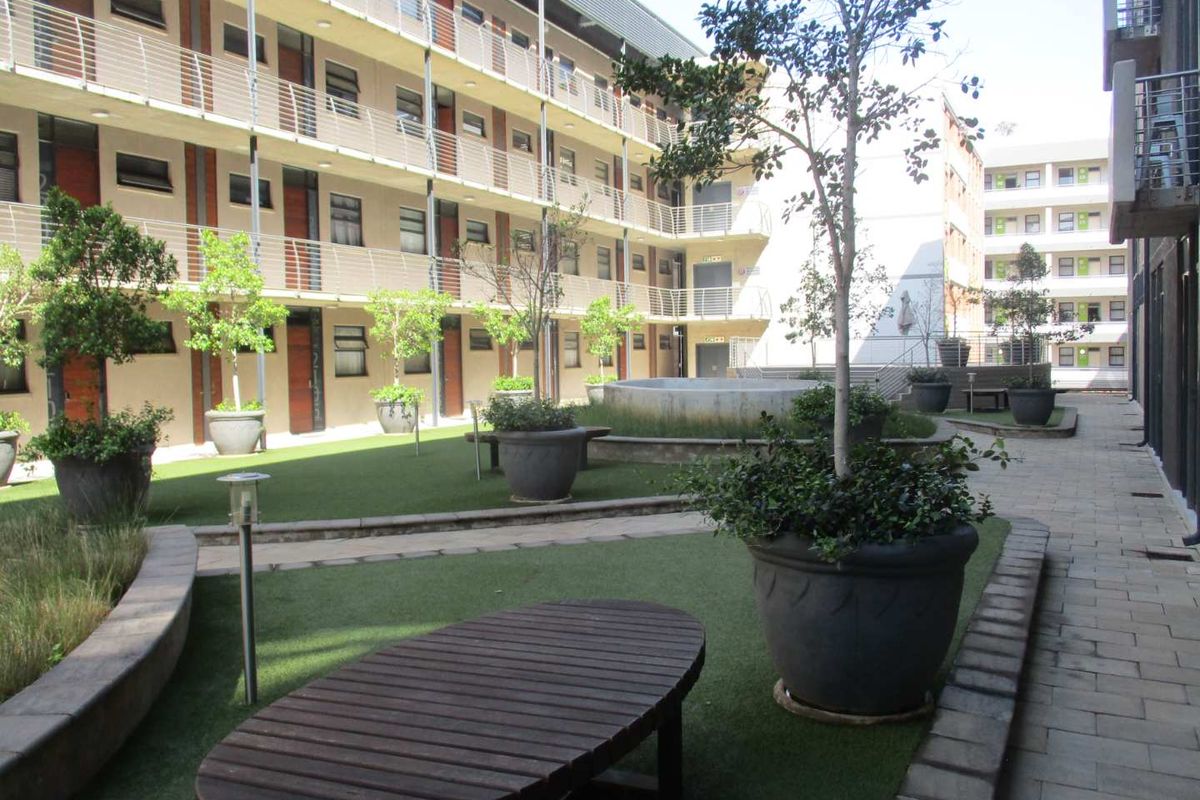 A well-maintained communal courtyard area within an apartment complex, featuring artificial turf, paved pathways, and established landscaping.