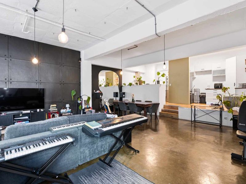 Spacious open-plan office area featuring polished concrete floors, exposed industrial ceiling details, and a raised platform section with integrated cabinetry.