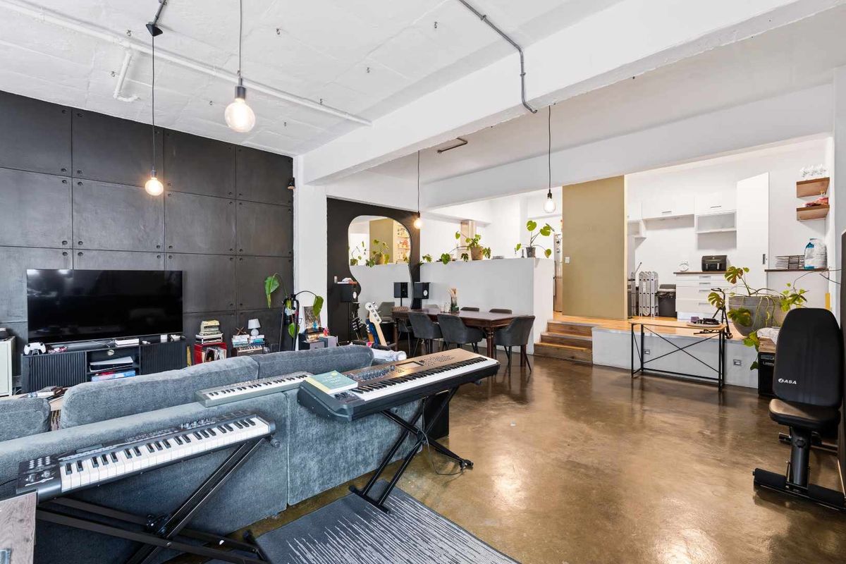 Spacious open-plan office area featuring polished concrete floors, exposed industrial ceiling details, and a raised platform section with integrated cabinetry.