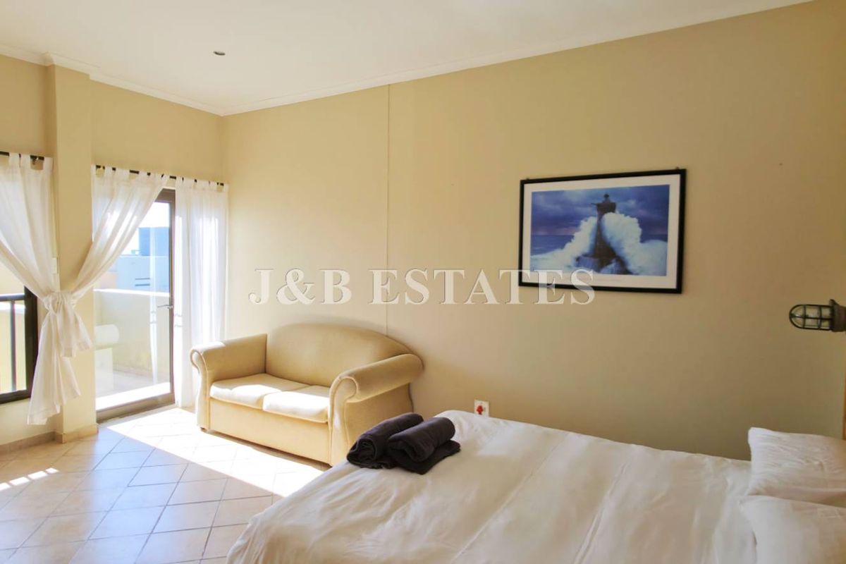 Spacious bedroom featuring tiled flooring, neutral walls, and direct access to a private balcony through sliding glass doors.