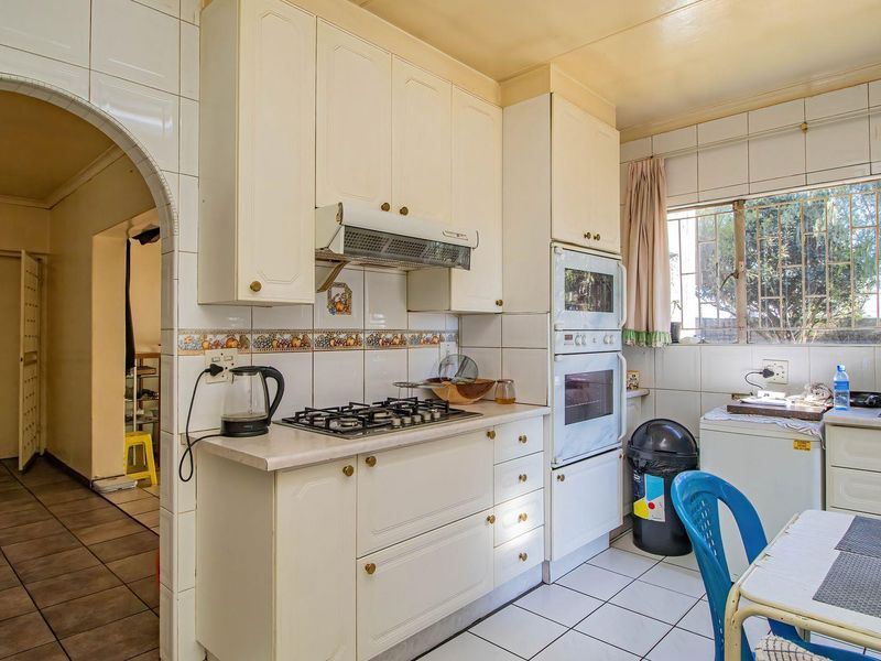 Functional kitchen featuring built-in cabinetry, gas hob, extractor fan, and double oven with tiled splashbacks and flooring.