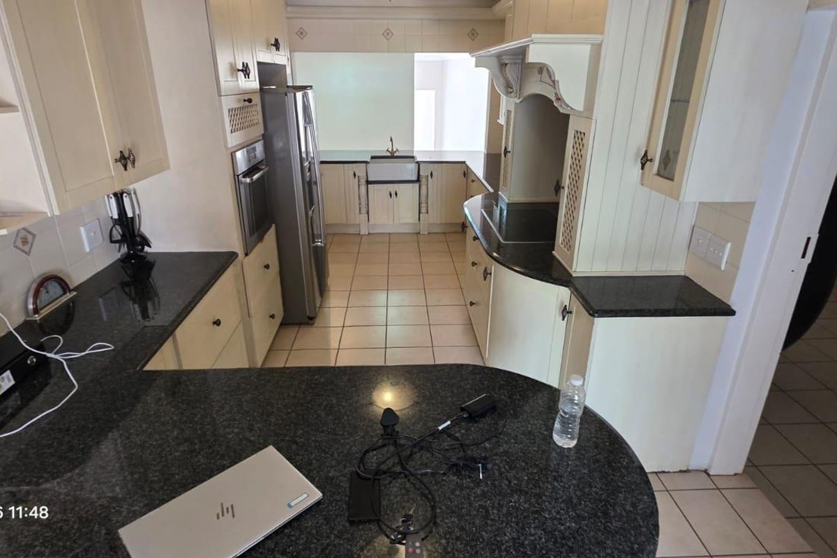 A functional kitchen featuring granite countertops, custom cabinetry, a farmhouse sink, and built-in oven, with tiled flooring throughout.