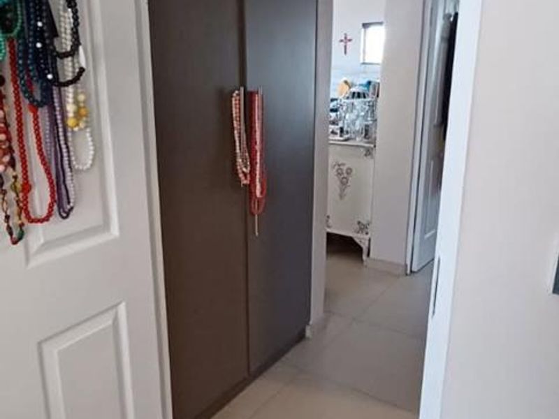 A clean hallway featuring neutral tiled flooring and built-in cupboards, providing functional storage space within the apartment.