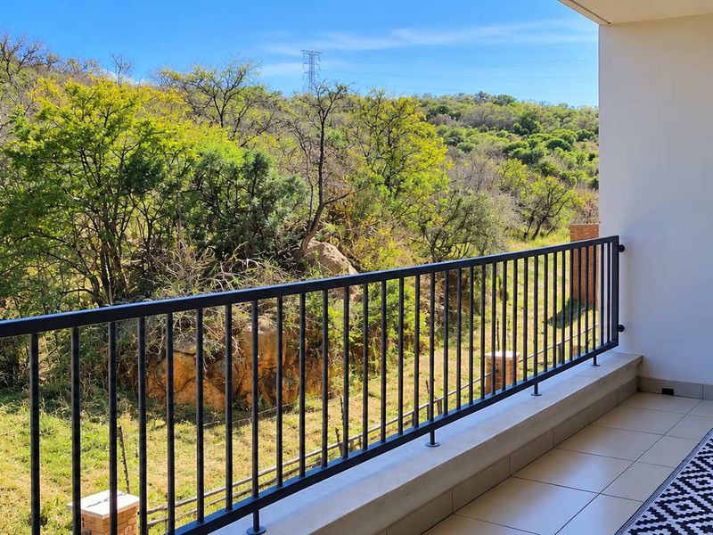 A private balcony featuring a modern metal balustrade and tiled flooring, offering scenic views of the surrounding natural landscape.