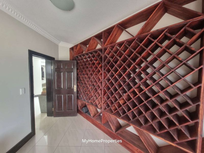 A dedicated wine cellar area featuring extensive built-in timber lattice wine racking, tiled flooring, and decorative ceiling cornicing.