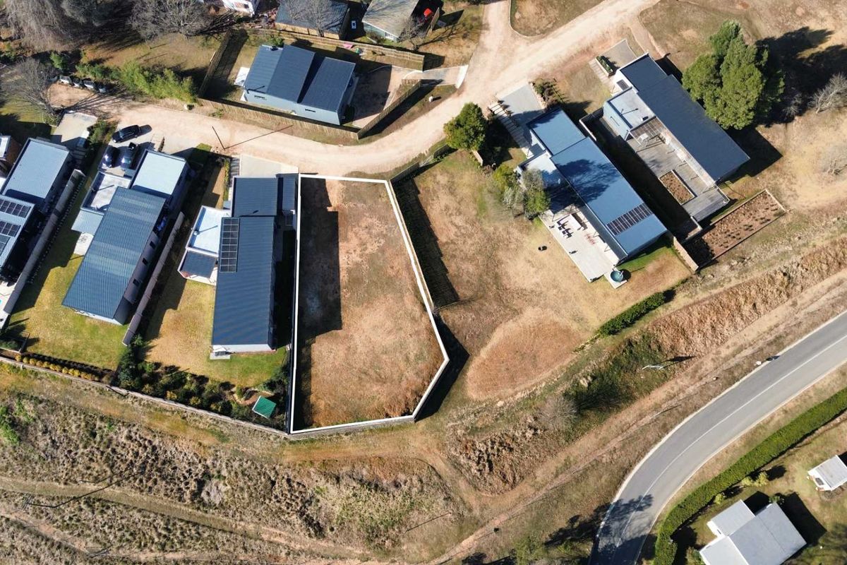 Aerial view of a vacant residential plot situated within a developed estate, featuring clear boundary lines and surrounding residential properties.