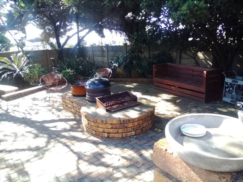 Outdoor patio area featuring brick paving and a built-in brick braai, set within a private garden space.