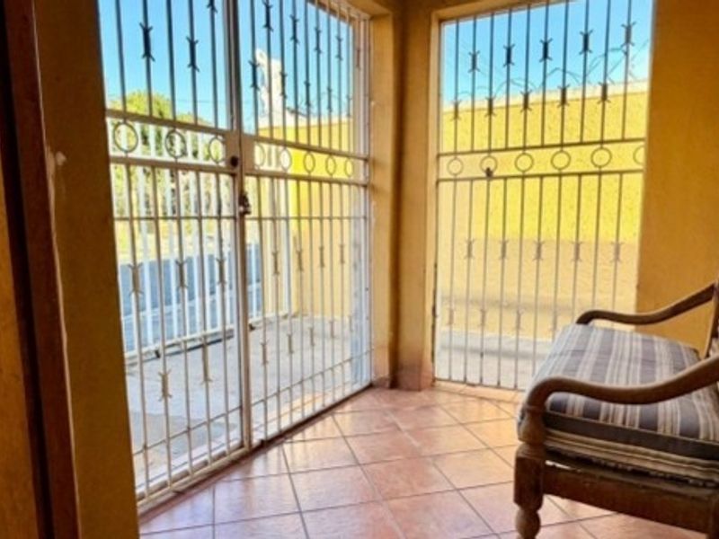 A covered patio area featuring tiled flooring and secure metal security gates, providing a protected transition space between the interior and exterior.