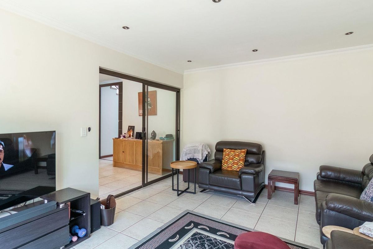A living room featuring tiled flooring, recessed ceiling lighting, and a sliding glass door leading to an adjacent room.