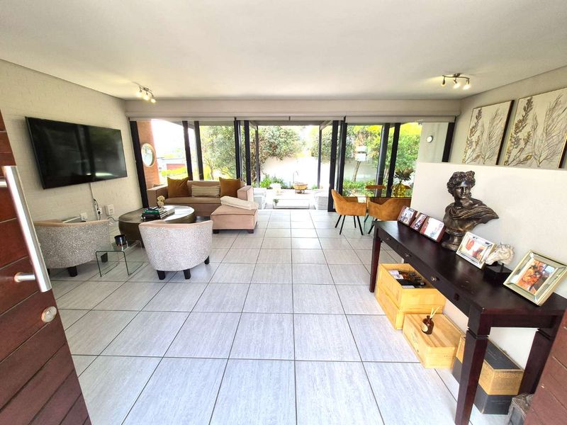 Spacious open-plan living area featuring large format floor tiles, a textured brick wall, and expansive sliding glass doors opening to a private patio.