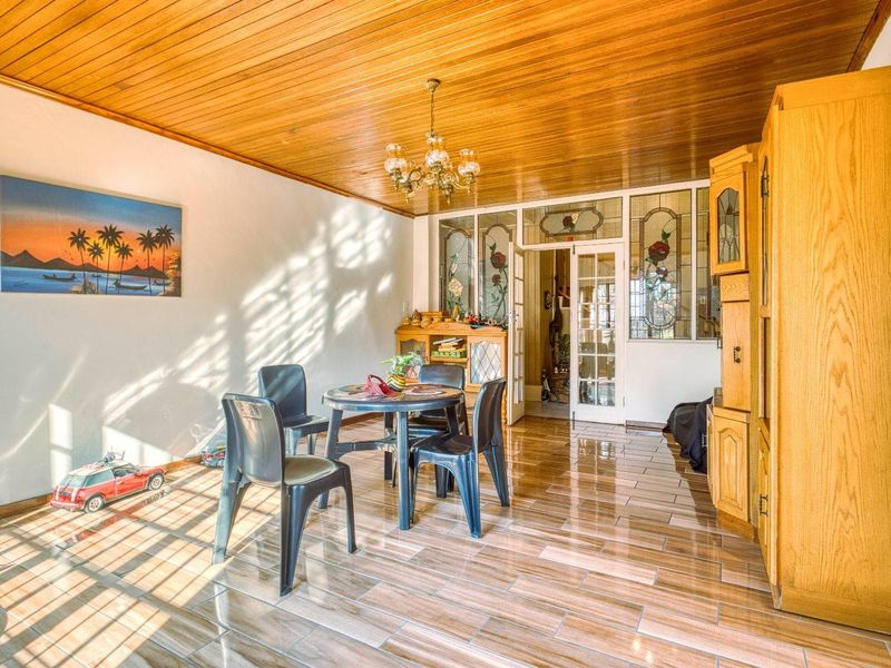 A dining room featuring a warm timber-clad ceiling, ceramic tiled flooring, and decorative leaded glass internal doors and panels.