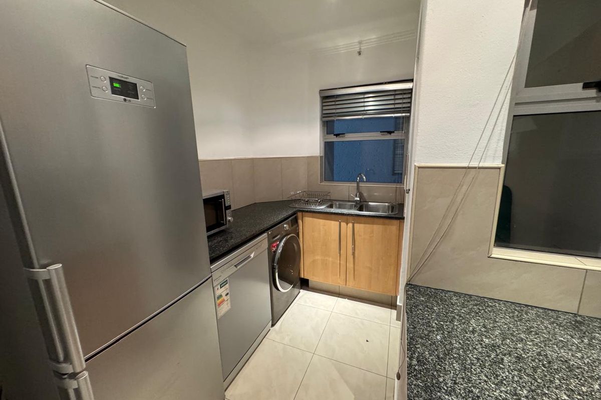 Compact kitchen featuring granite countertops, tiled splashbacks, double sink, and built-in cabinetry with space for under-counter appliances.