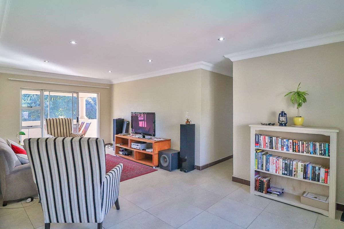 Spacious living area featuring neutral tiled flooring, recessed downlighting, and sliding glass doors providing access to an outdoor patio space.