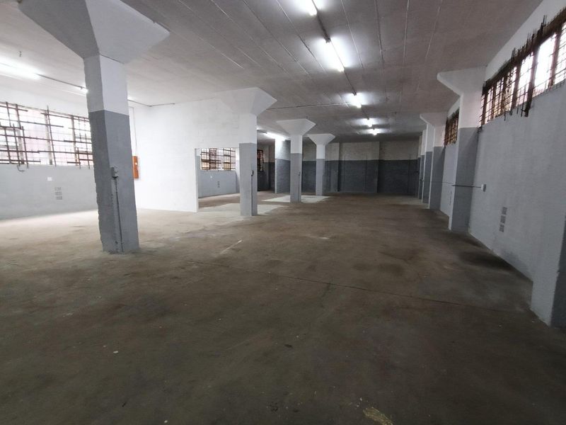 Spacious industrial utility area featuring concrete flooring, structural columns, and fluorescent lighting, suitable for storage or workshop use.