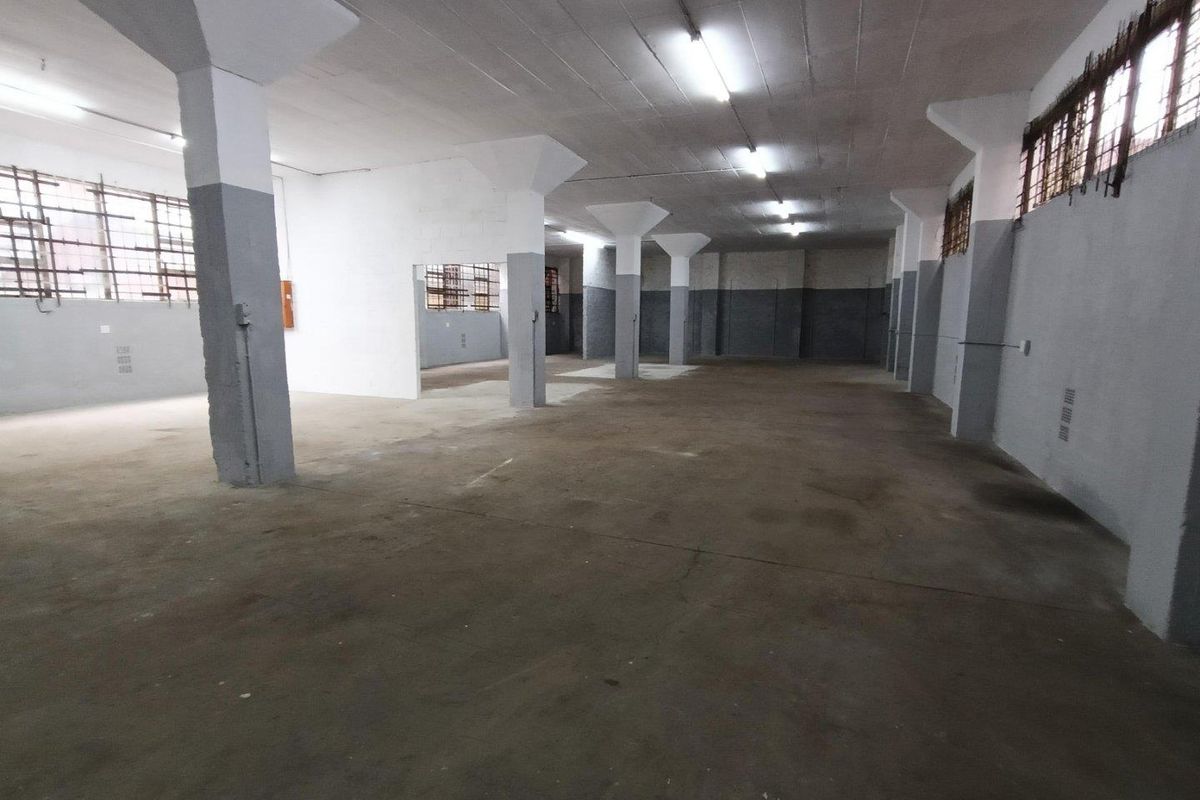 Spacious industrial utility area featuring concrete flooring, structural columns, and fluorescent lighting, suitable for storage or workshop use.