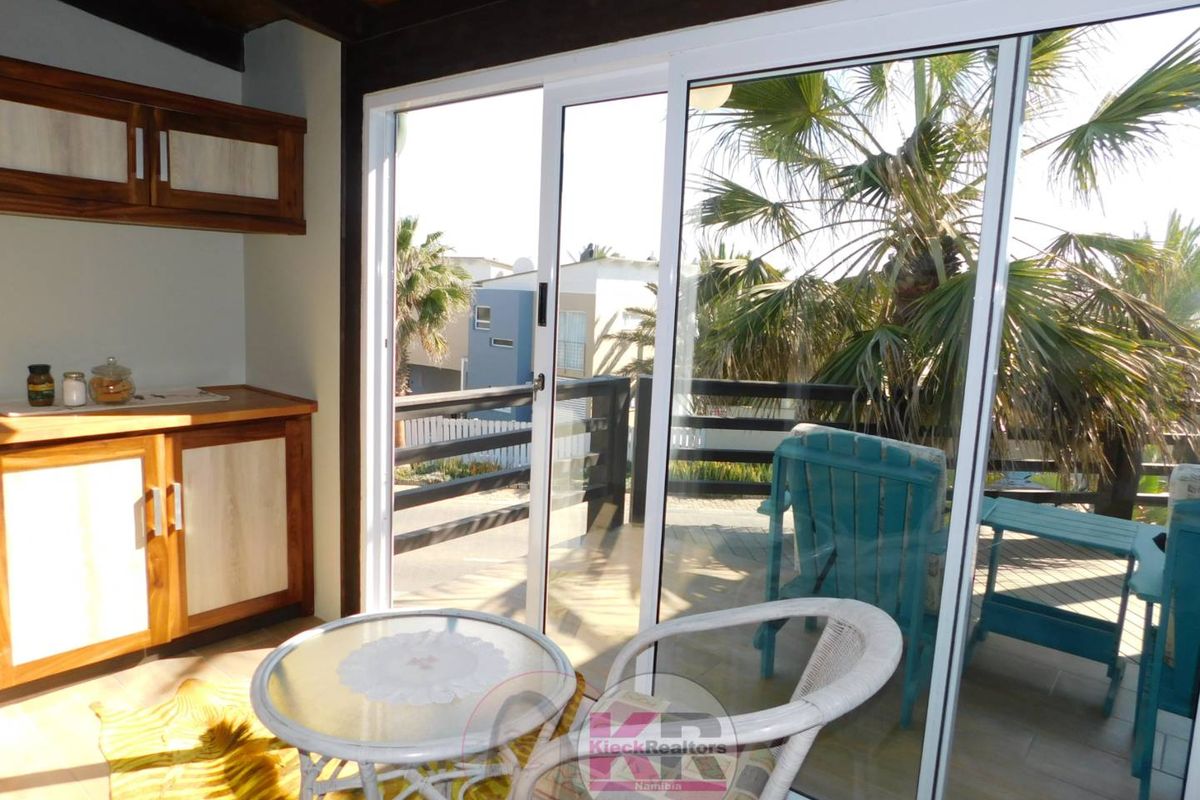 A bright living area featuring built-in wooden cabinetry and large sliding glass doors that open onto an outdoor patio space.