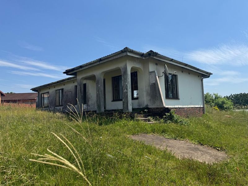 A detached single-story house requiring significant exterior renovation and landscaping, featuring a covered porch and security bars on windows.