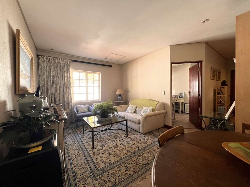 A comfortable living room area featuring neutral wall tones, recessed lighting, and a doorway leading to an adjacent room.
