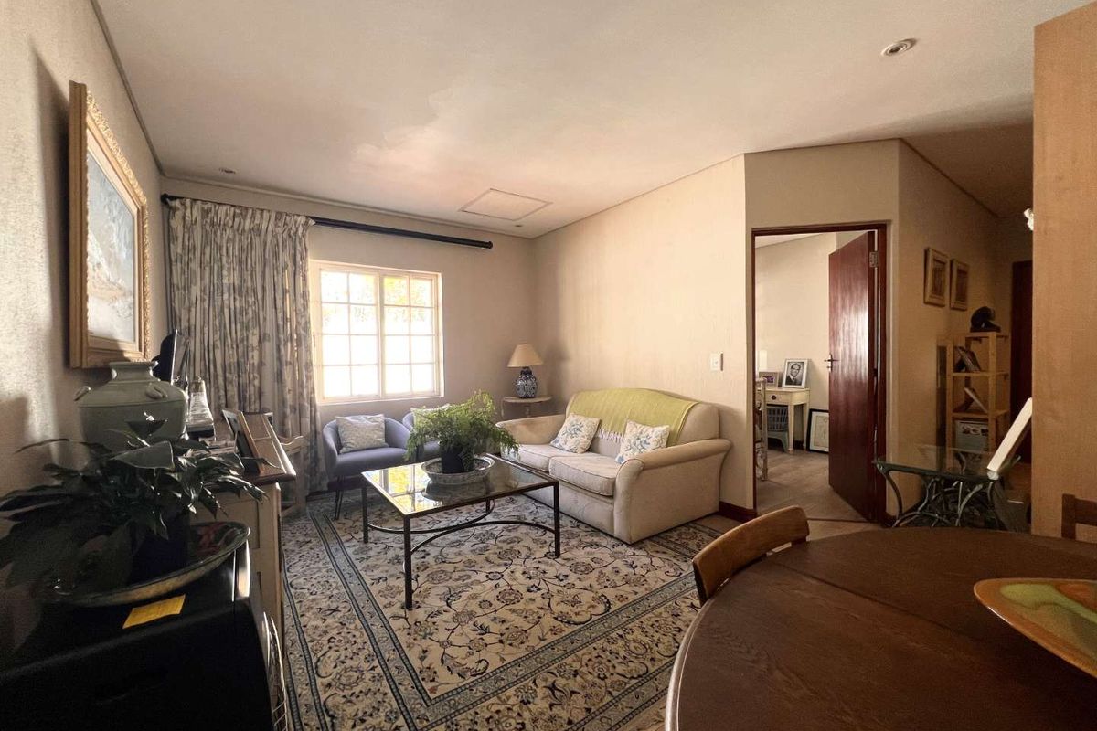 A comfortable living room area featuring neutral wall tones, recessed lighting, and a doorway leading to an adjacent room.