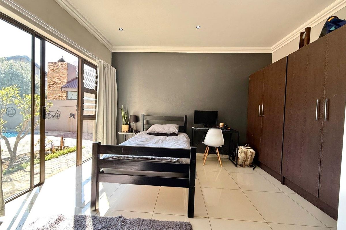 Spacious bedroom featuring large sliding glass doors providing natural light, tiled flooring, built-in cupboards, and direct access to the outdoor area.
