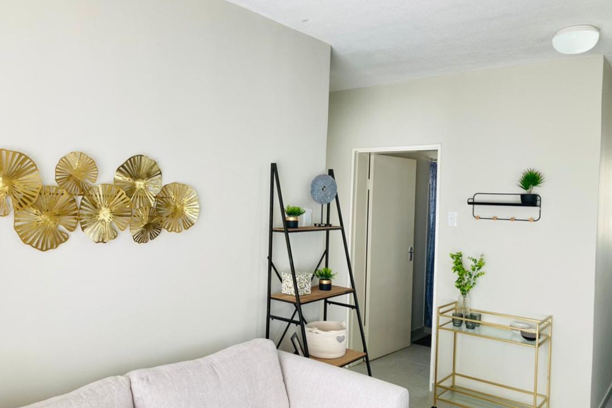 A bright and neutral living area featuring tiled flooring and a flush mount ceiling light, providing a clean and welcoming space.