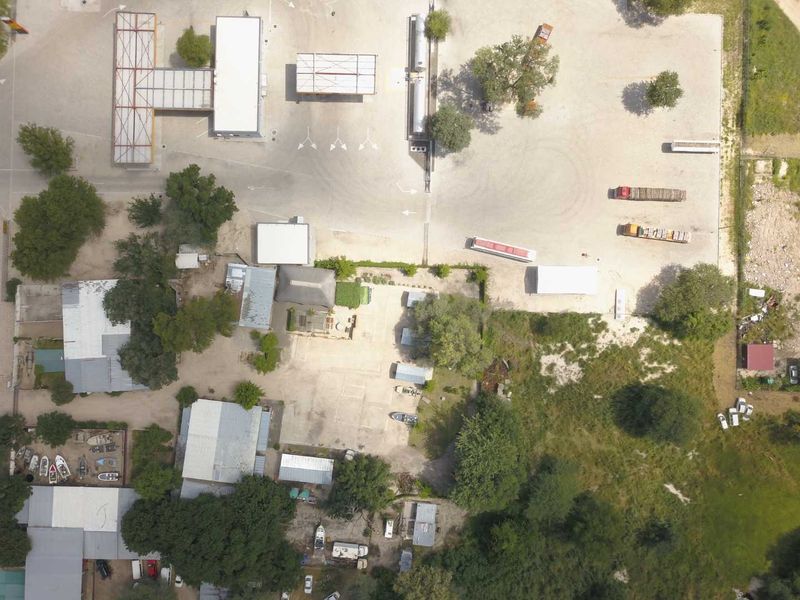 Aerial view of a mixed-use property featuring a fuel station, multiple outbuildings, and extensive gravel yard space.