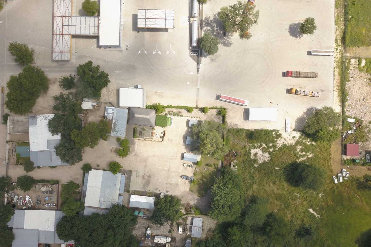 Aerial view of a mixed-use property featuring a fuel station, multiple outbuildings, and extensive gravel yard space.