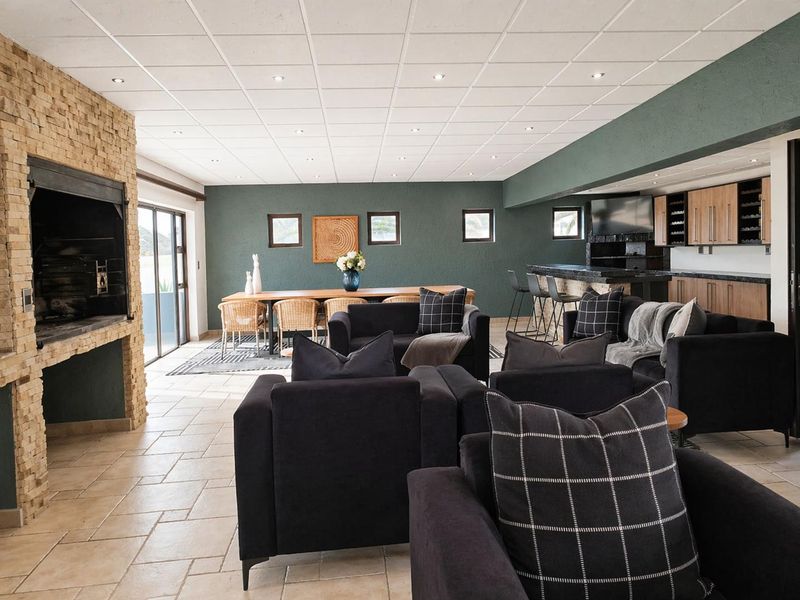 Spacious open-plan living area featuring a built-in stone fireplace, tiled flooring, recessed lighting, and a dedicated bar area with integrated cabinetry.