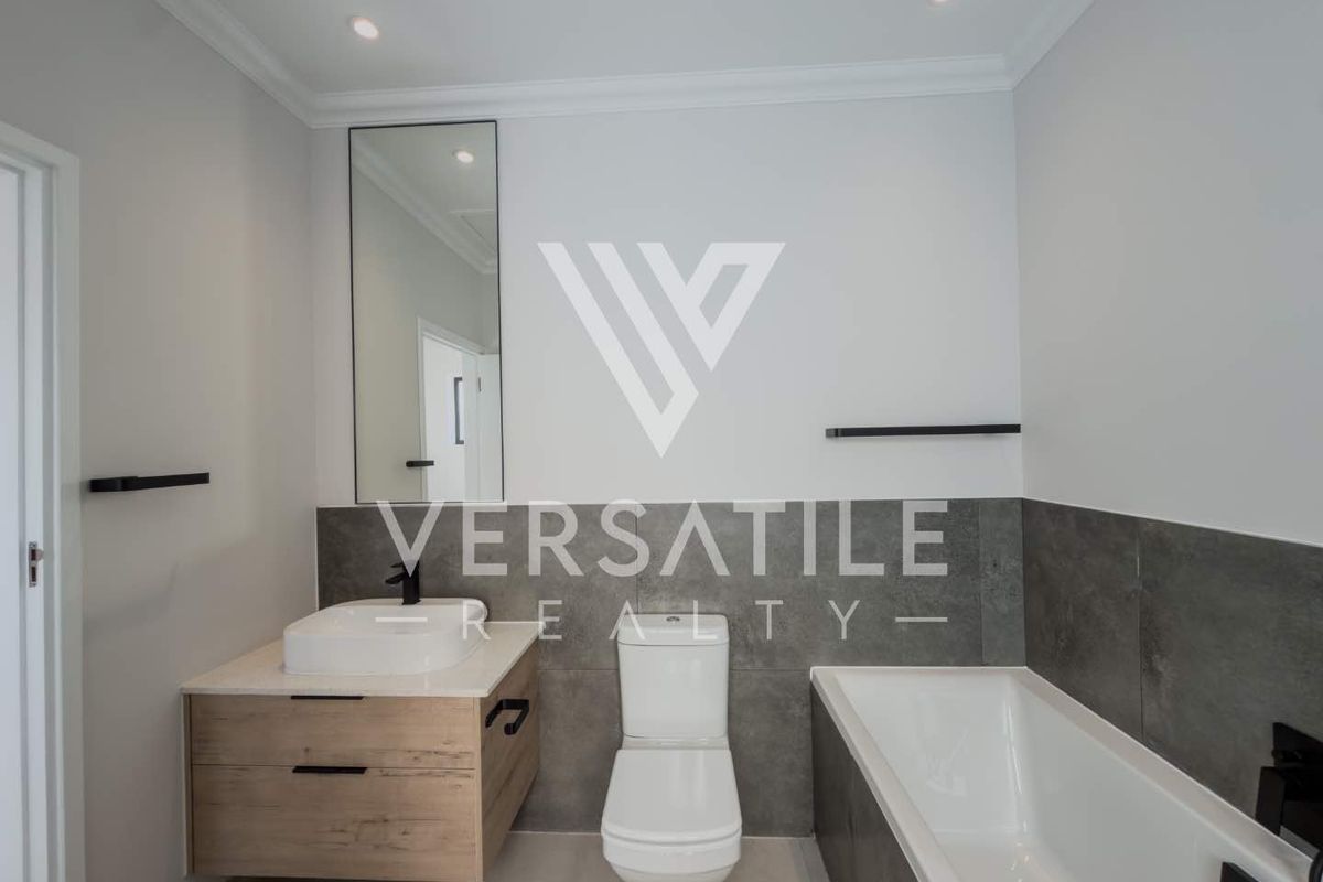Modern bathroom featuring a floating vanity, vessel sink, built-in bathtub, and contemporary grey tiling with high-quality finishes.
