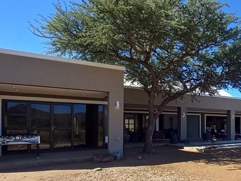 A spacious rear exterior view of the house featuring a large covered patio area with modern sliding glass doors and recessed lighting.