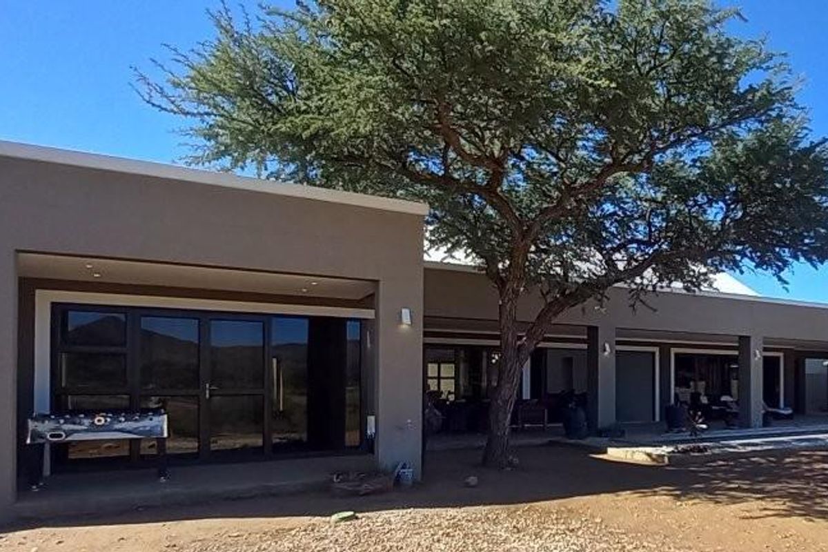 A spacious rear exterior view of the house featuring a large covered patio area with modern sliding glass doors and recessed lighting.