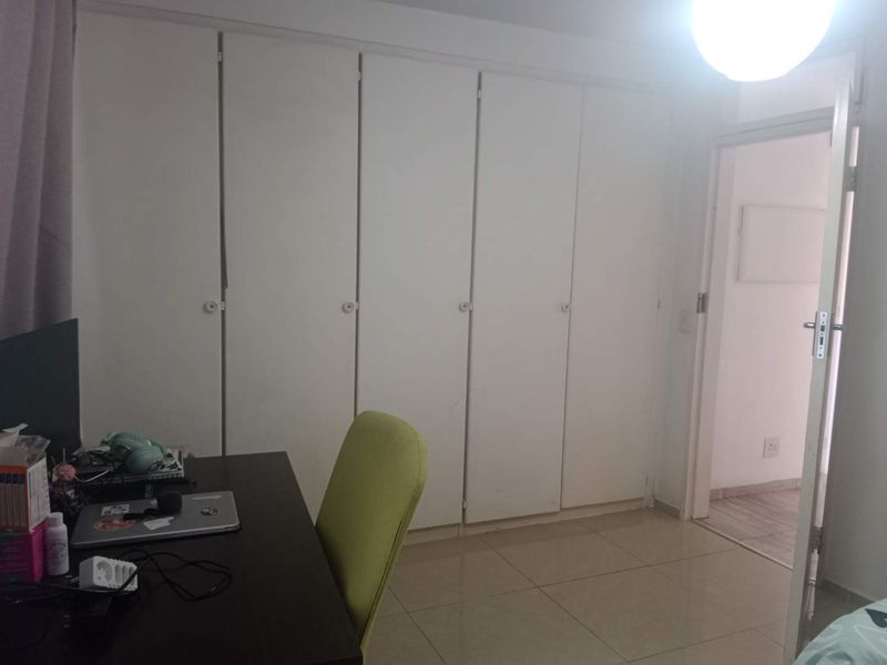 A bedroom featuring built-in cupboards and tiled flooring, providing functional storage space within the apartment.