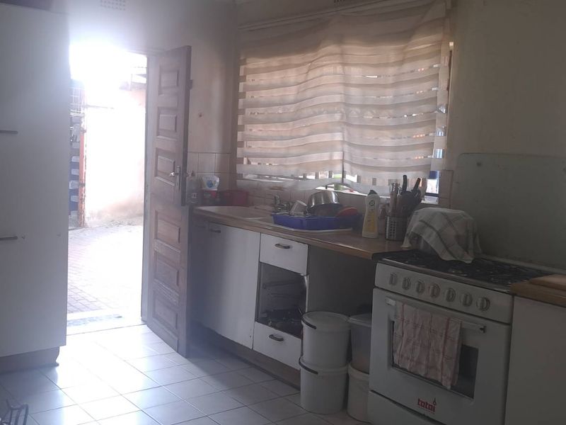 Functional kitchen featuring tiled flooring, built-in cabinetry, and a freestanding stove, with direct access to the exterior.