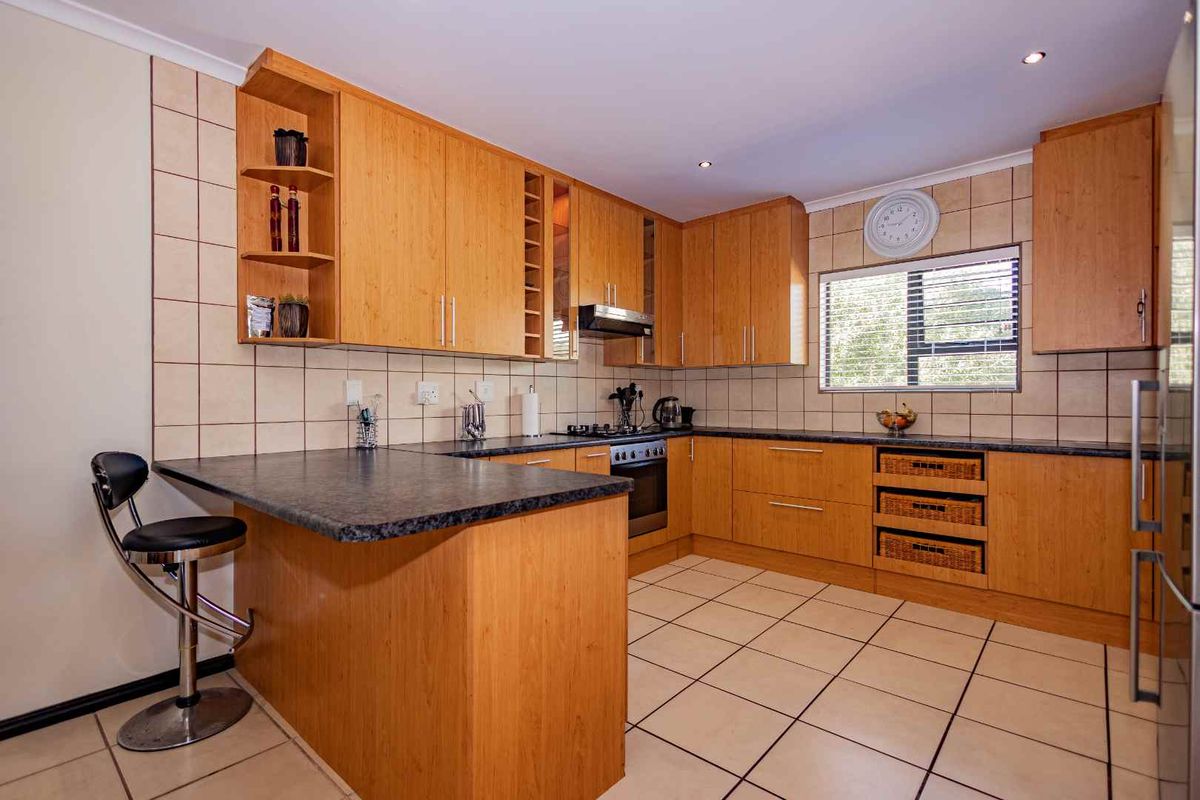A functional kitchen featuring light wood cabinetry, dark granite countertops, tiled backsplash, and a breakfast nook counter.