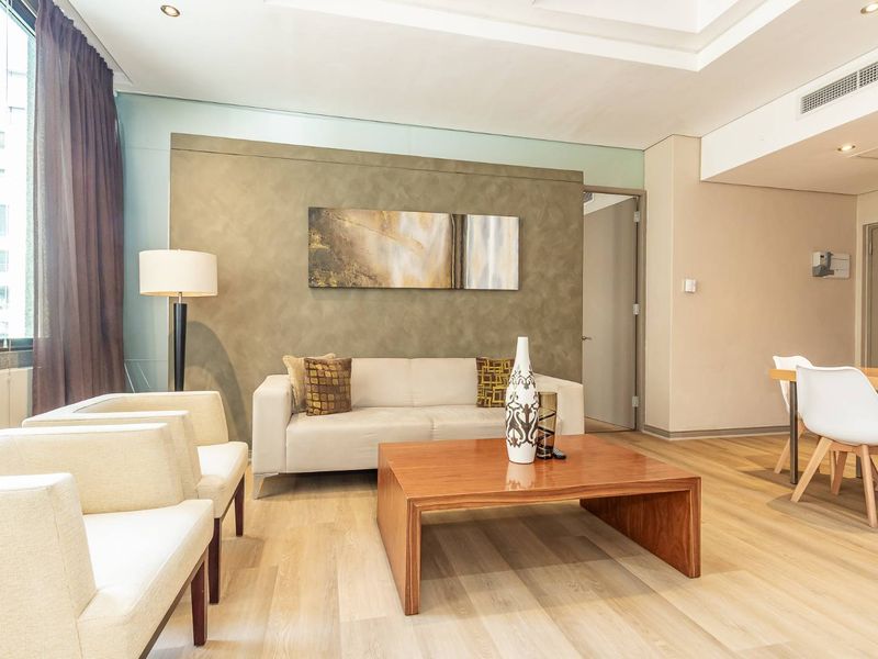 A bright open-plan living and dining area featuring modern laminate flooring, a textured feature wall, and integrated ducted air conditioning.