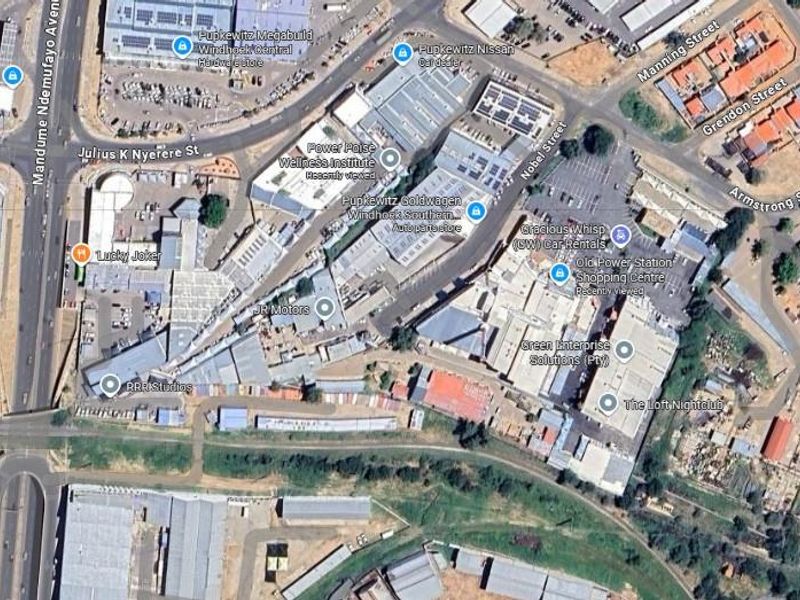 An aerial view of a commercial and industrial district featuring various office and retail buildings, parking areas, and surrounding road infrastructure.