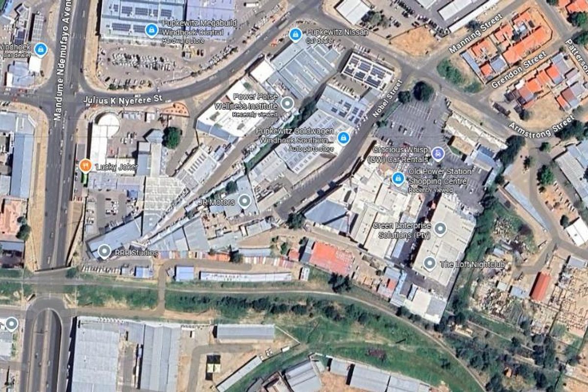 An aerial view of a commercial and industrial district featuring various office and retail buildings, parking areas, and surrounding road infrastructure.