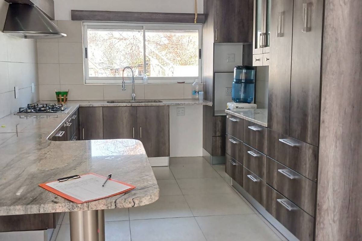 Modern kitchen featuring dark wood-grain cabinetry, stone countertops, a gas hob with extractor fan, and tiled flooring.